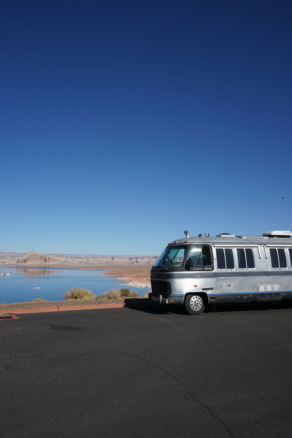 Classic motorhome parked at a paved desert overlook under a clear sky